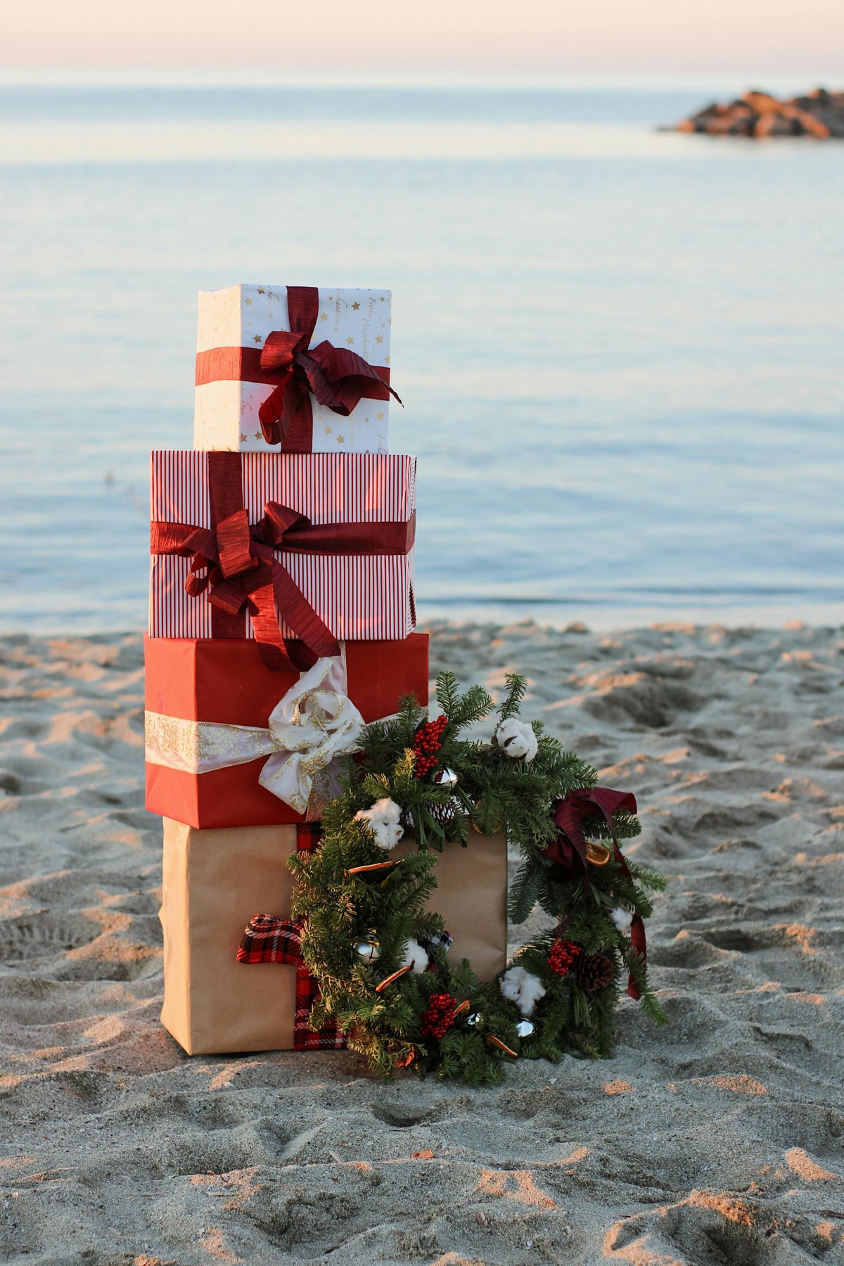 Wrapped Christmas gifts and an evergreen wreath beside the water