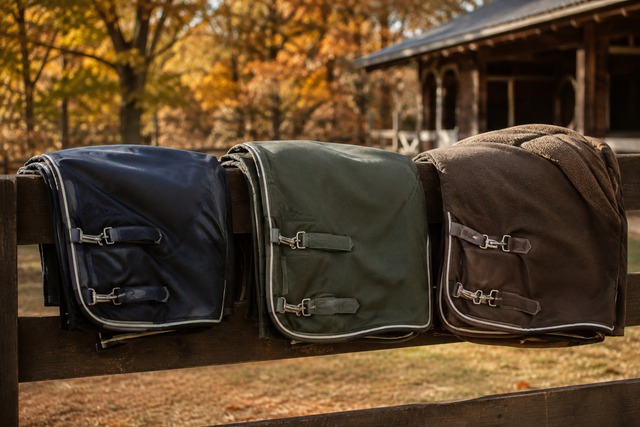 Three horse blankets in lightweight, medium, and heavyweight styles displayed on a stable fence