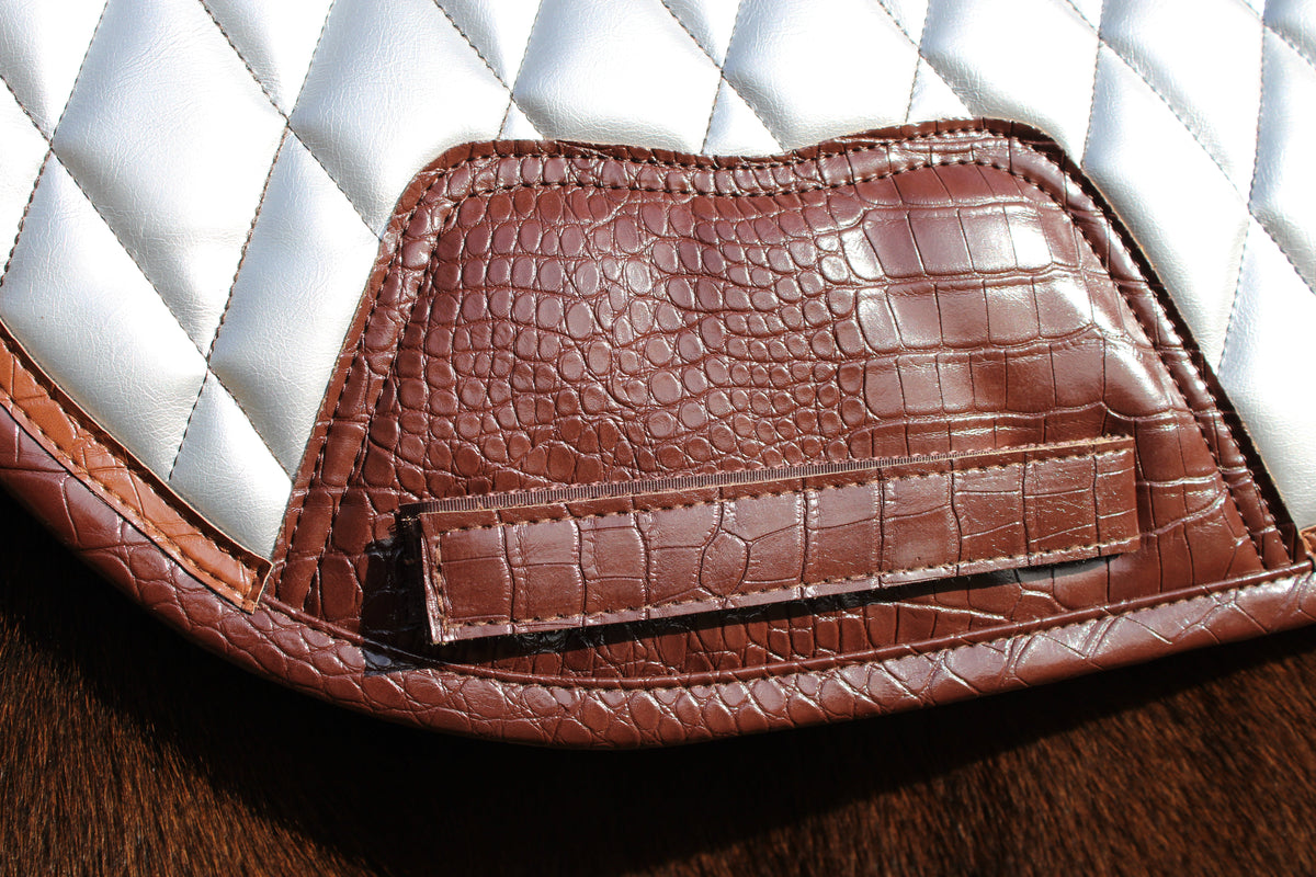 San Eligius chrome quilted jump saddle pad with brown crocodile piping on horse under saddle