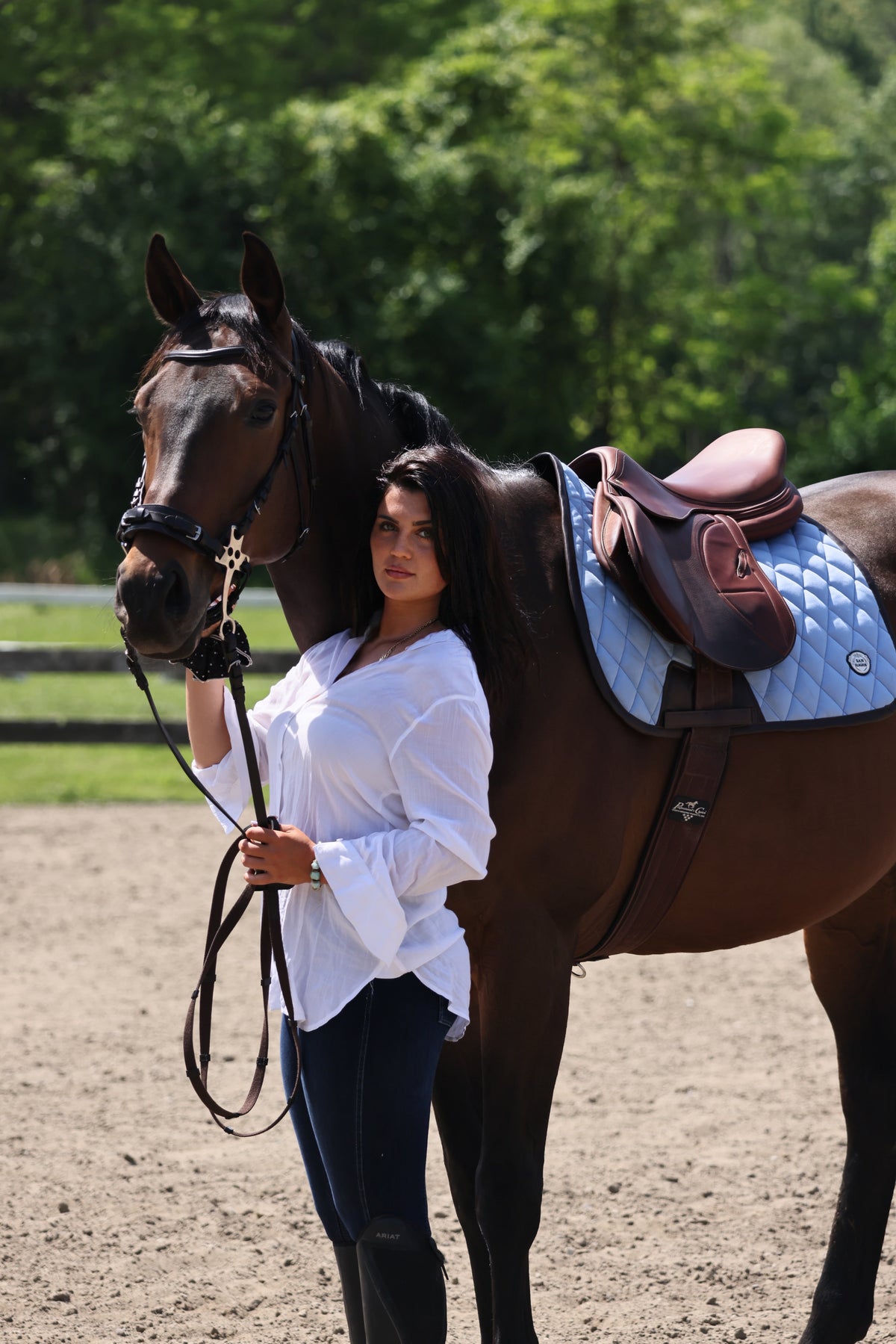 San Eligius light blue quilted jump saddle pad with brown leather piping on horse under saddle