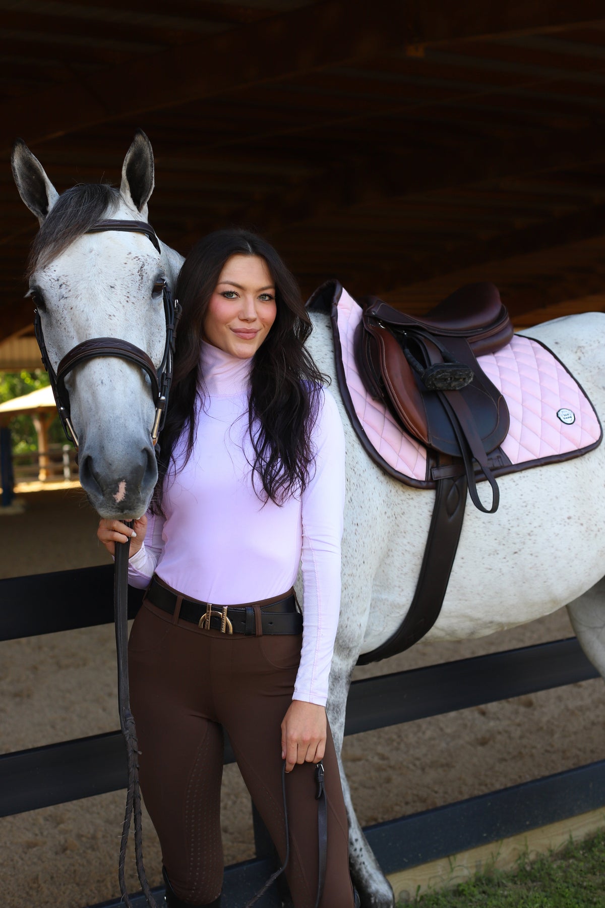 San Eligius pink quilted jump saddle pad with brown leather piping on horse under saddle