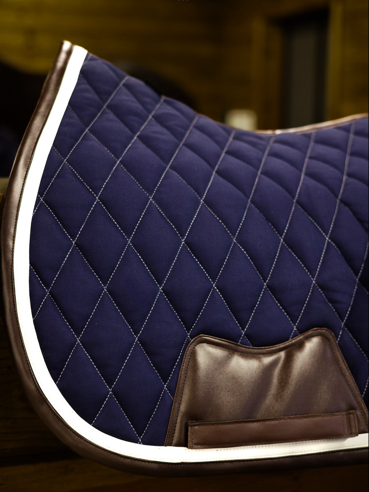 San Eligius navy quilted jump saddle pad with white and brown leather piping, lifestyle shot on horse