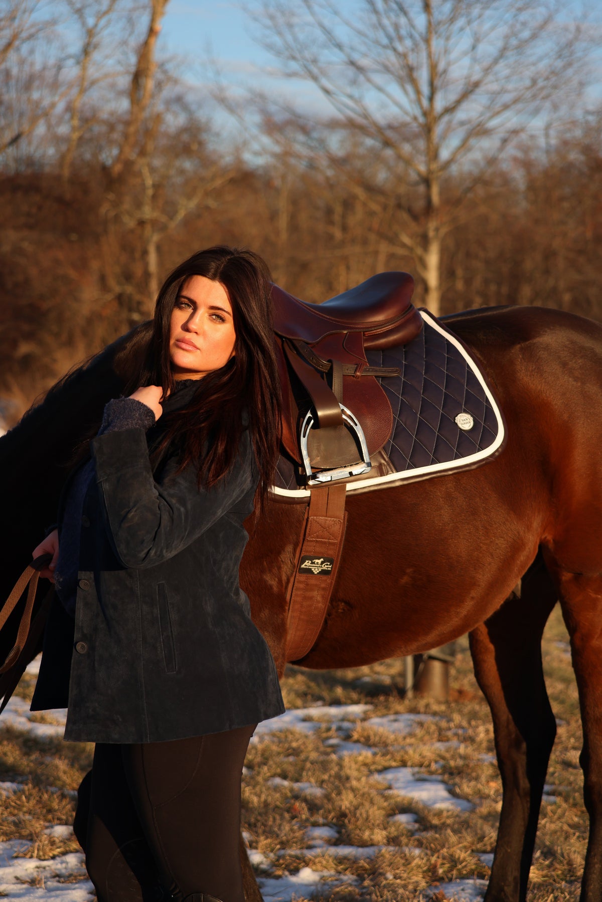 San Eligius navy quilted jump saddle pad with white and brown leather piping, outdoor lifestyle shot