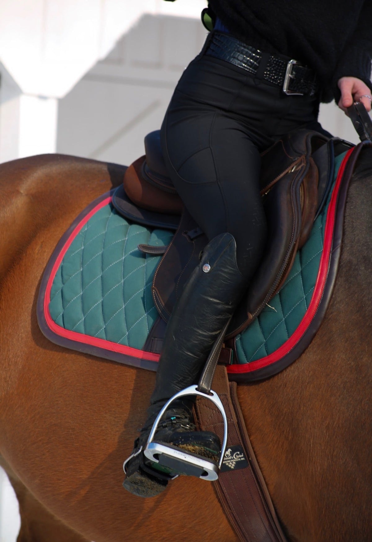 San Eligius green quilted jump saddle pad with red and brown leather piping, detail of logo emblem