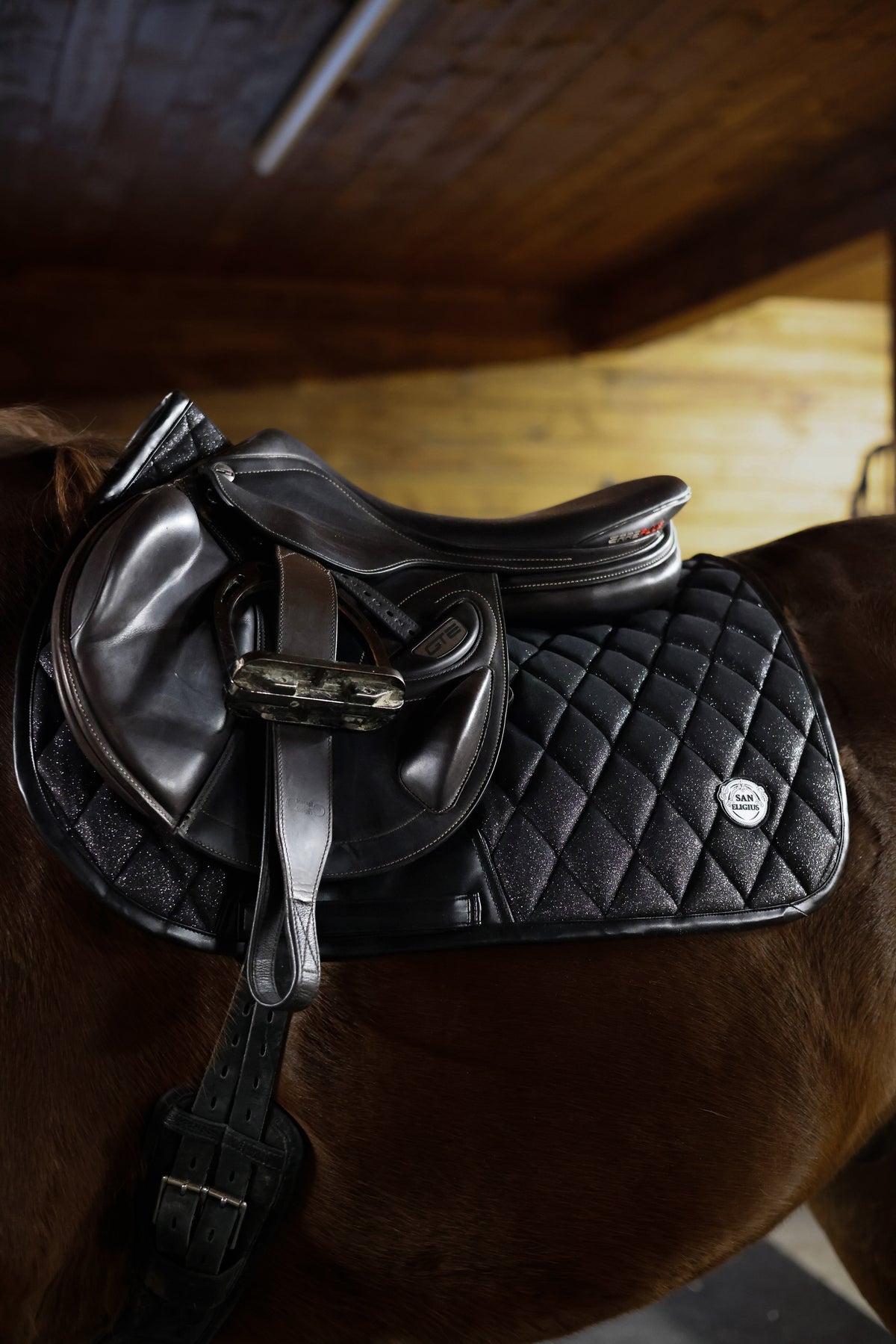 San Eligius Black Ice jump saddle pad with black leather piping, side profile view