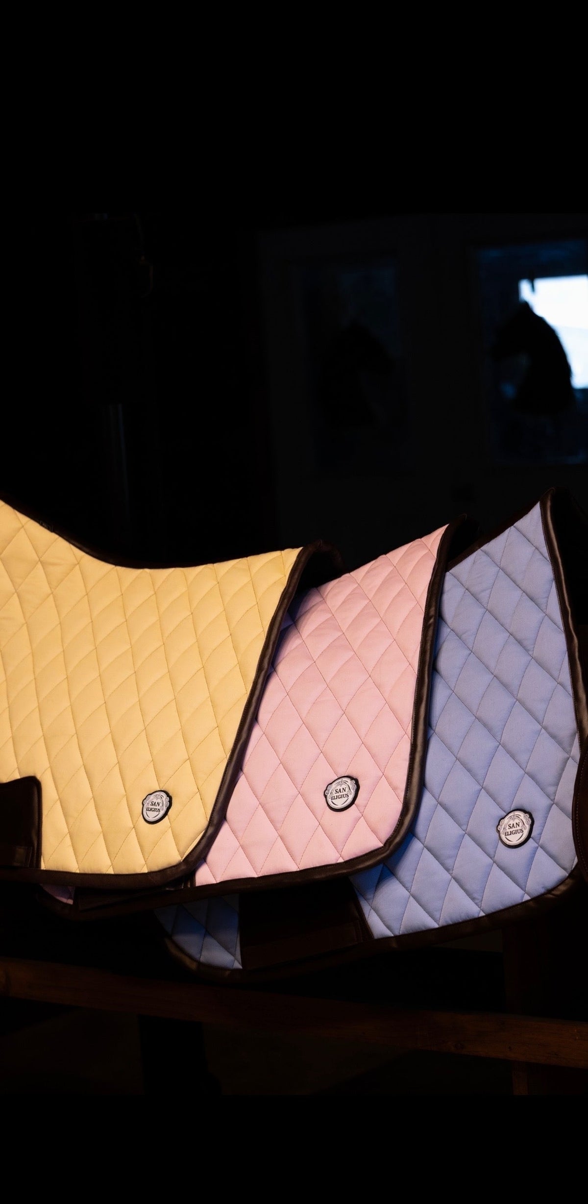 San Eligius pink quilted jump saddle pad with brown leather piping, angled view on horse