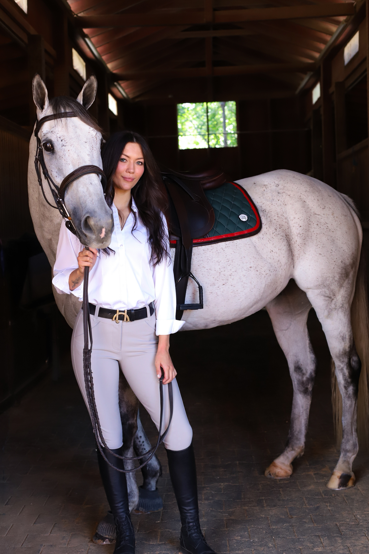San Eligius green quilted jump saddle pad with red and brown leather piping on horse under saddle