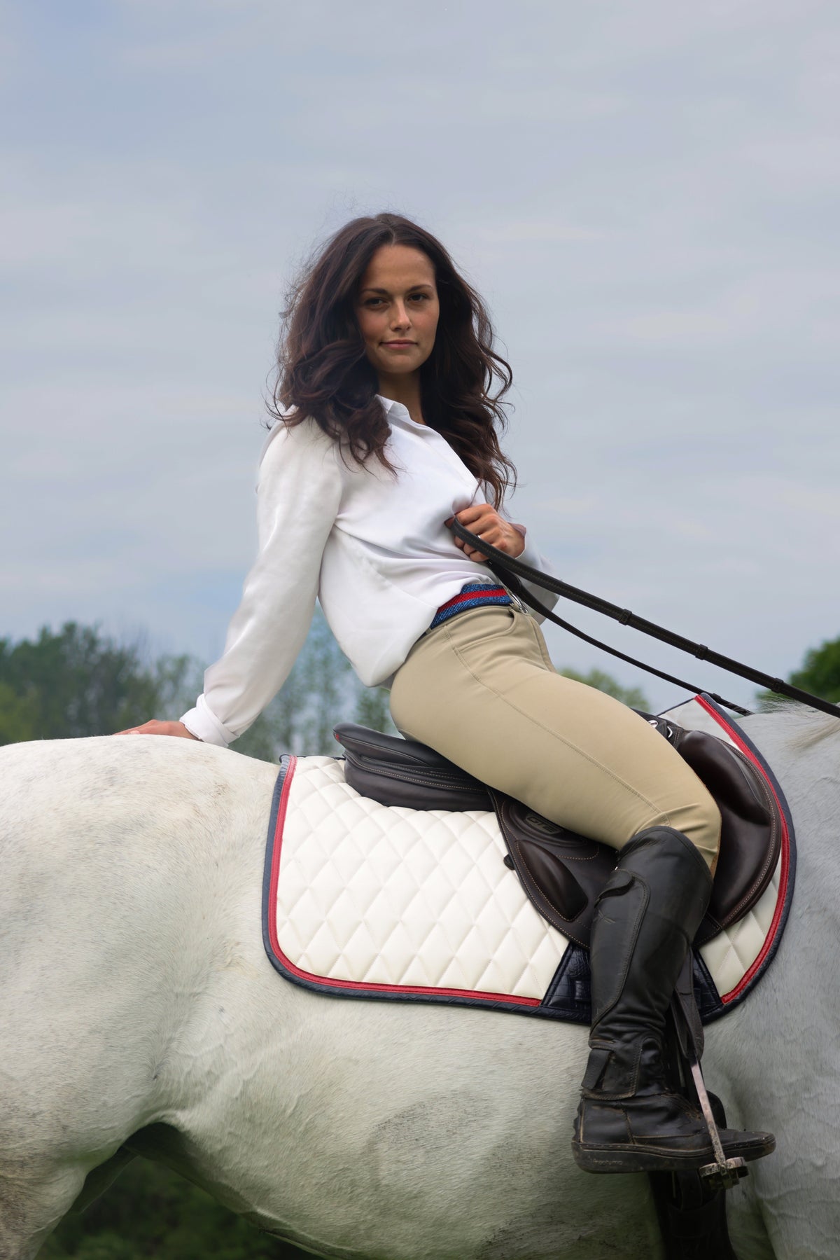 San Eligius white quilted jump saddle pad with red and navy crocodile piping, lifestyle shot on horse