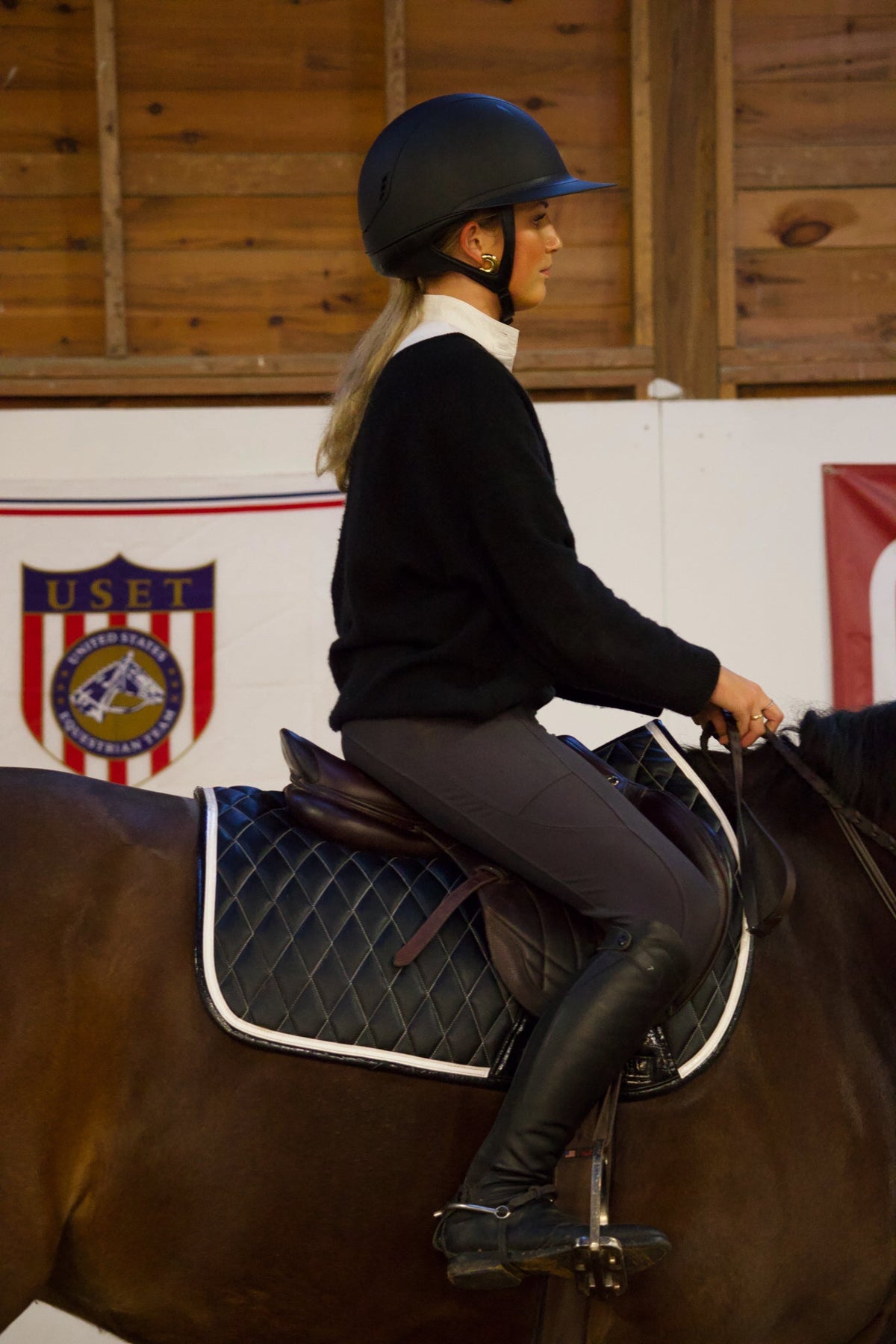 San Eligius black quilted jump saddle pad with white and black crocodile piping, outdoor lifestyle shot