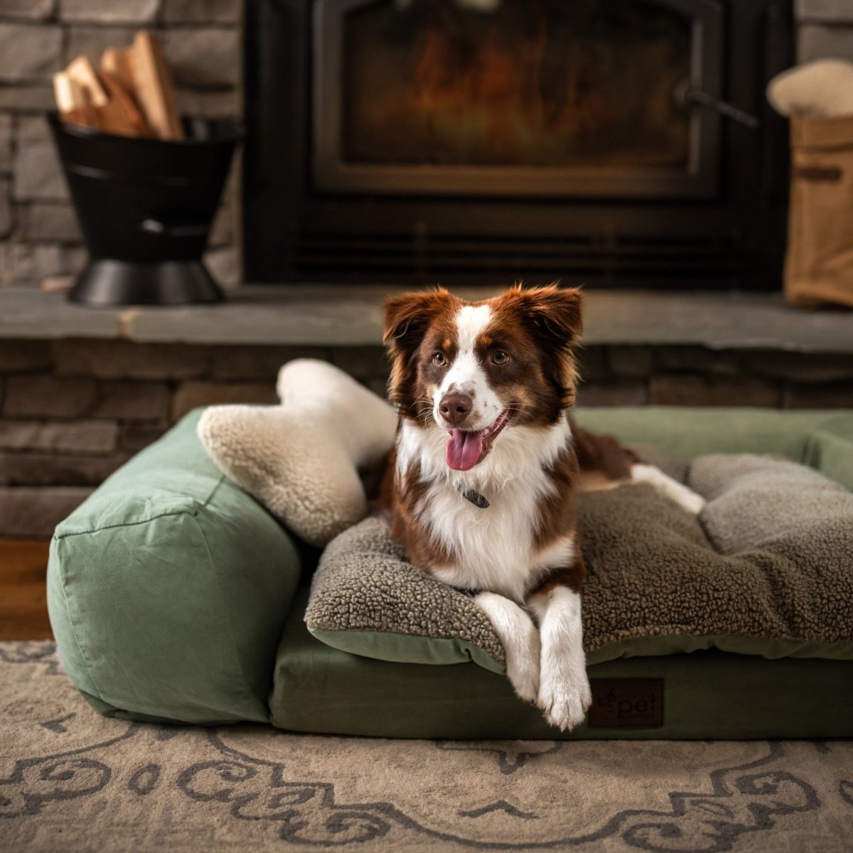 Dog resting on a luxury orthopedic dog bed with plush sherpa bolsters and supportive cushion by the fireplace.